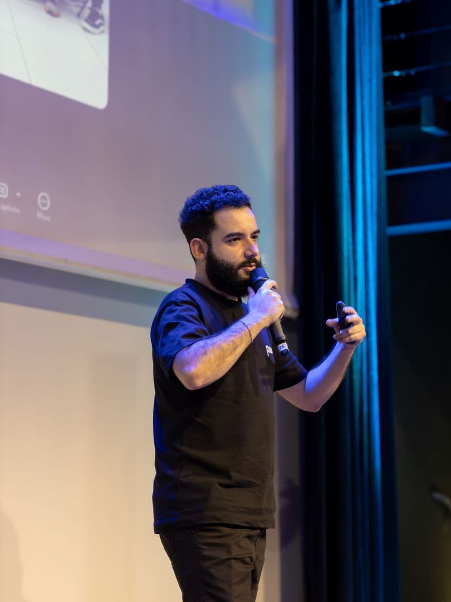 Speaker with a microphone presenting on stage in front of a projection screen
