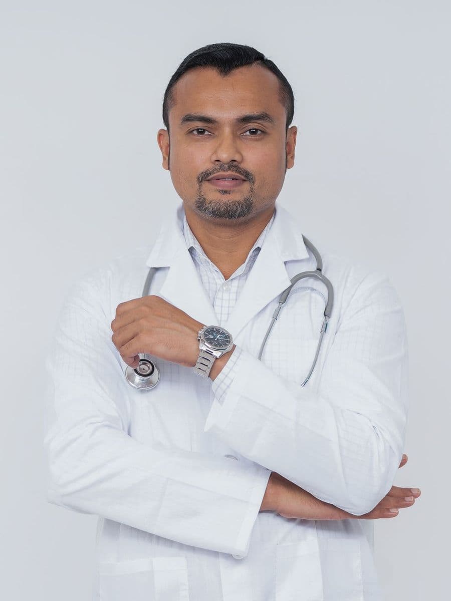 South Asian male doctor in a white coat with a stethoscope, arms folded