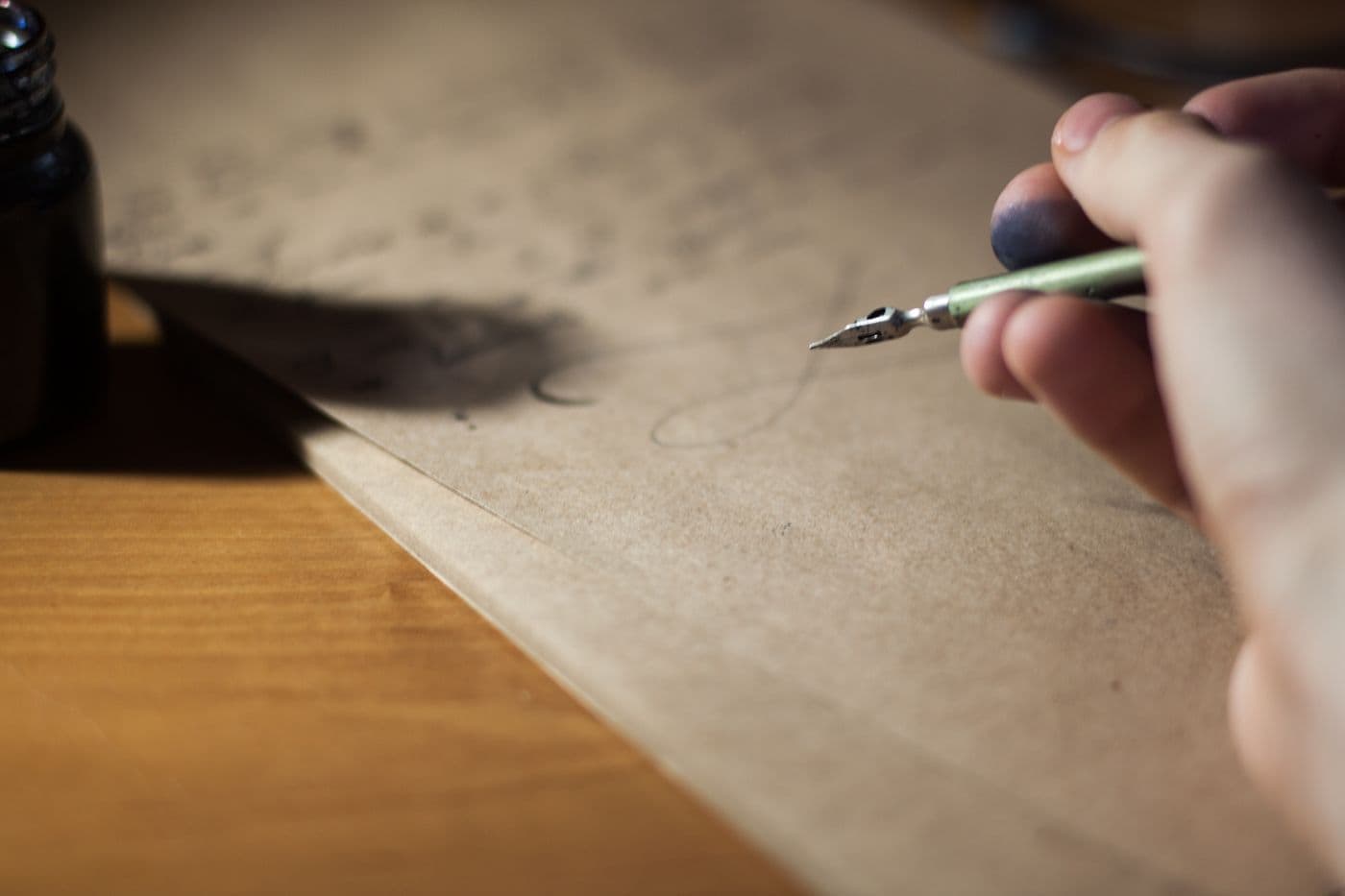 Hand writing with a fountain pen on paper on a wooden desk